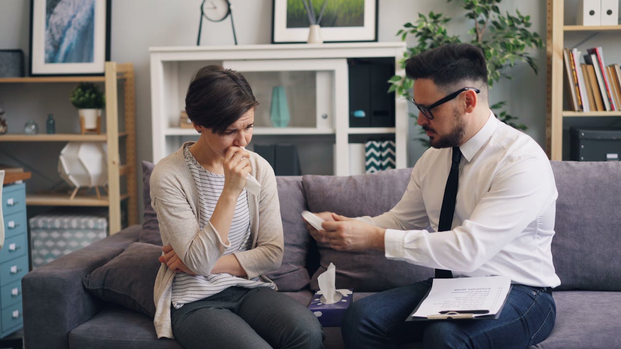A therapist provides support to a female patient during a counseling session.
